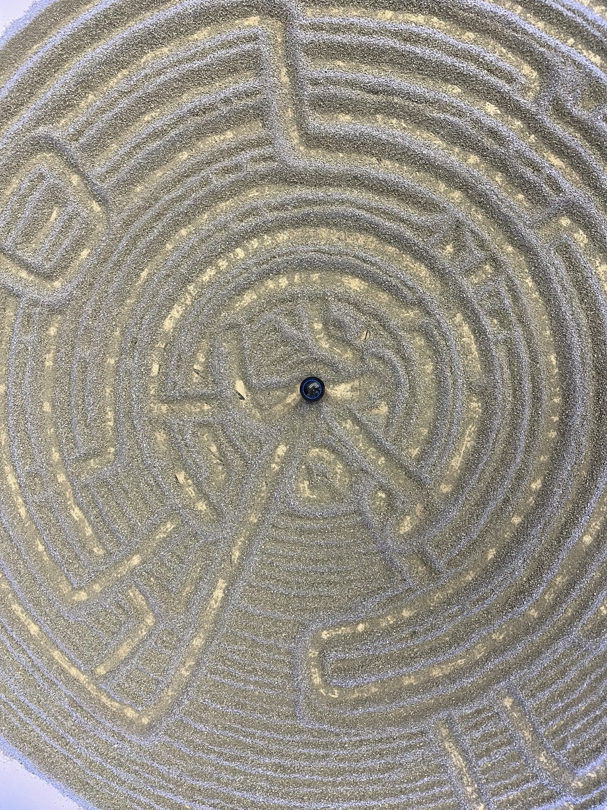 Top-down view of a labyrinth pattern drawn in the sand by the magnetic ball