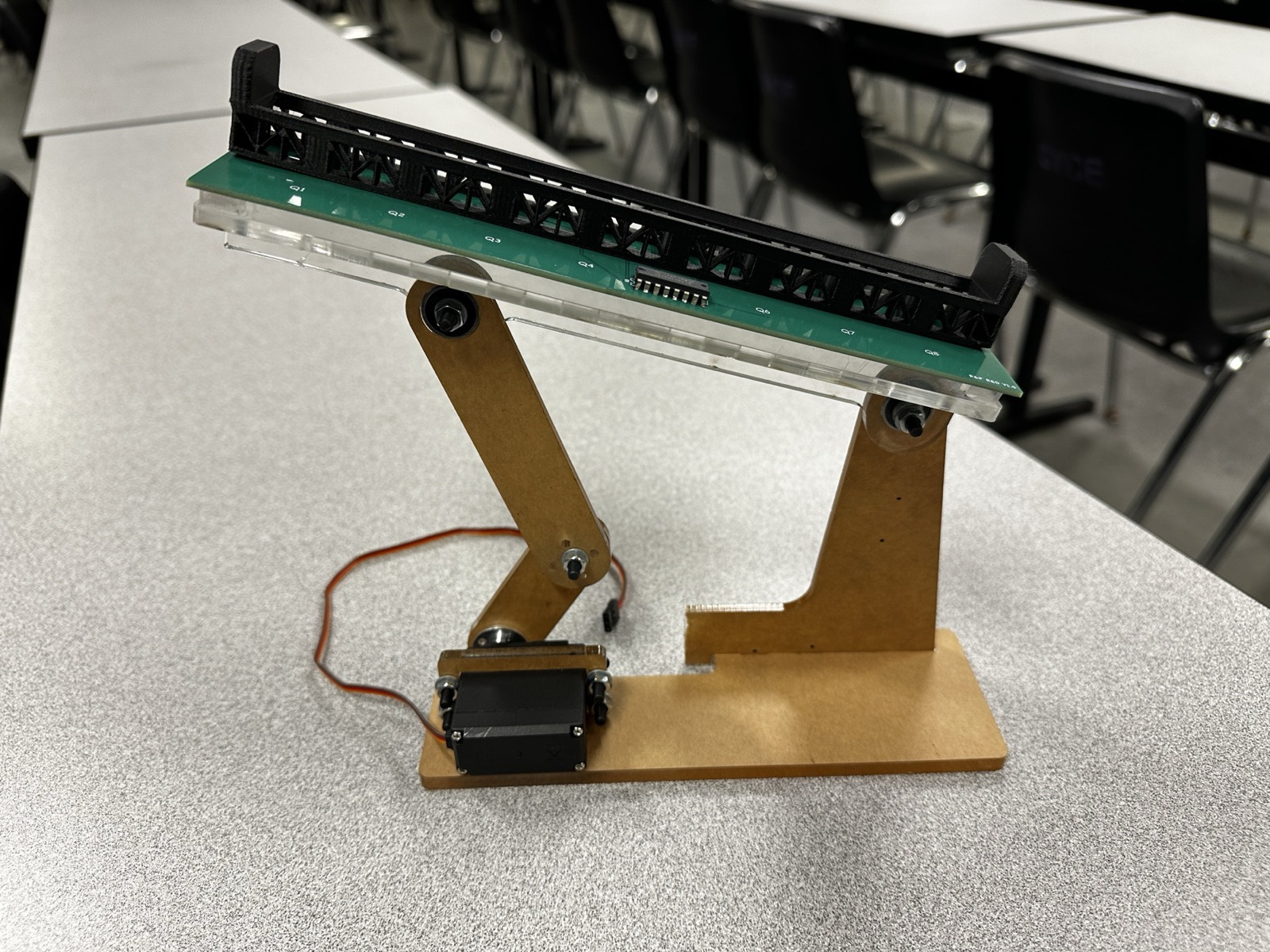 Front view of the build showing the servo cradle, bolted linkage joints, and phototransistor labels Q1 to Q8 on the PCB